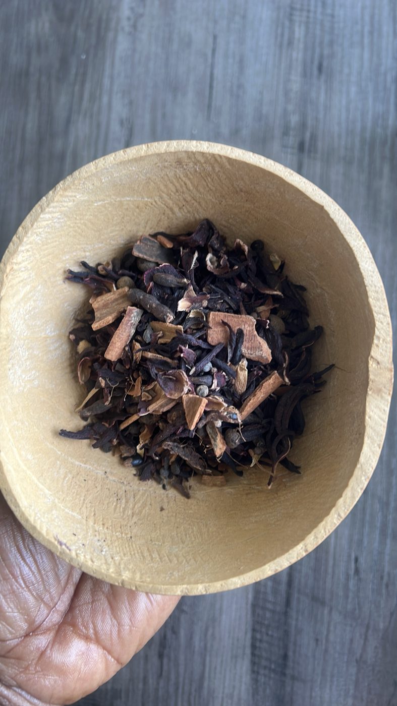 Loose blend of dried hibiscus, cinnamon bark and whole spices in a wooden bowl