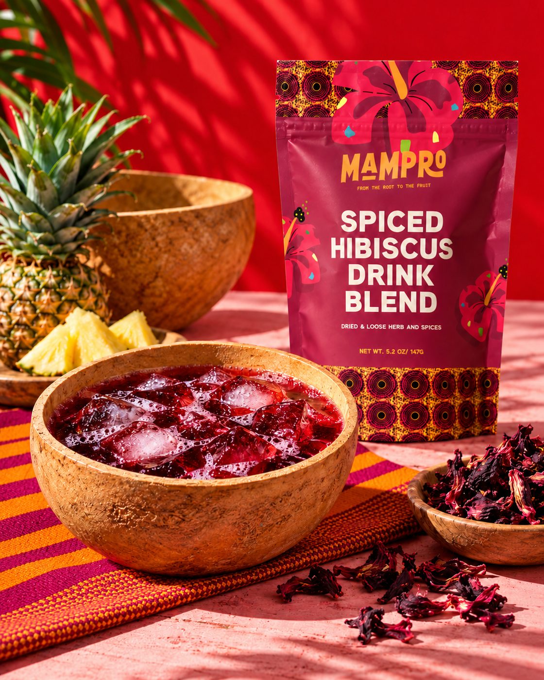 Mampro Spiced Hibiscus pouch beside a bowl of iced hibiscus, pineapple and dried hibiscus flowers